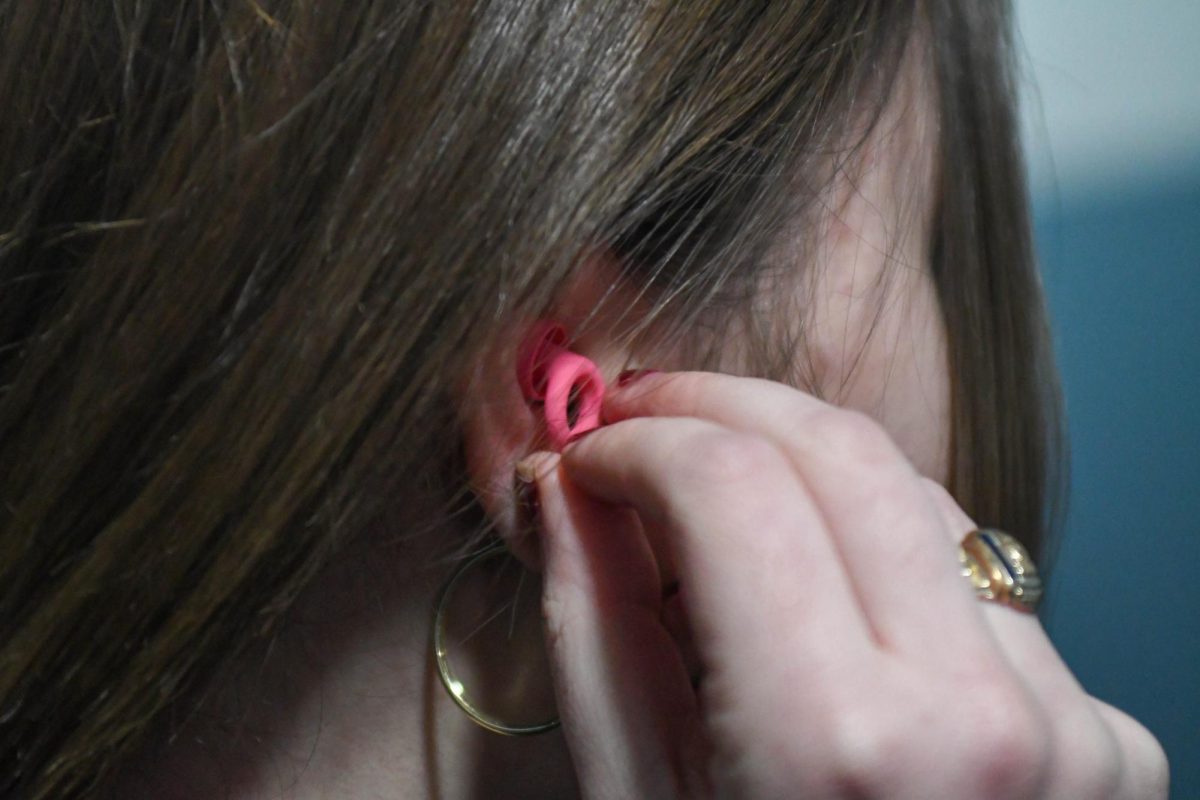A student puts in an earplug.
